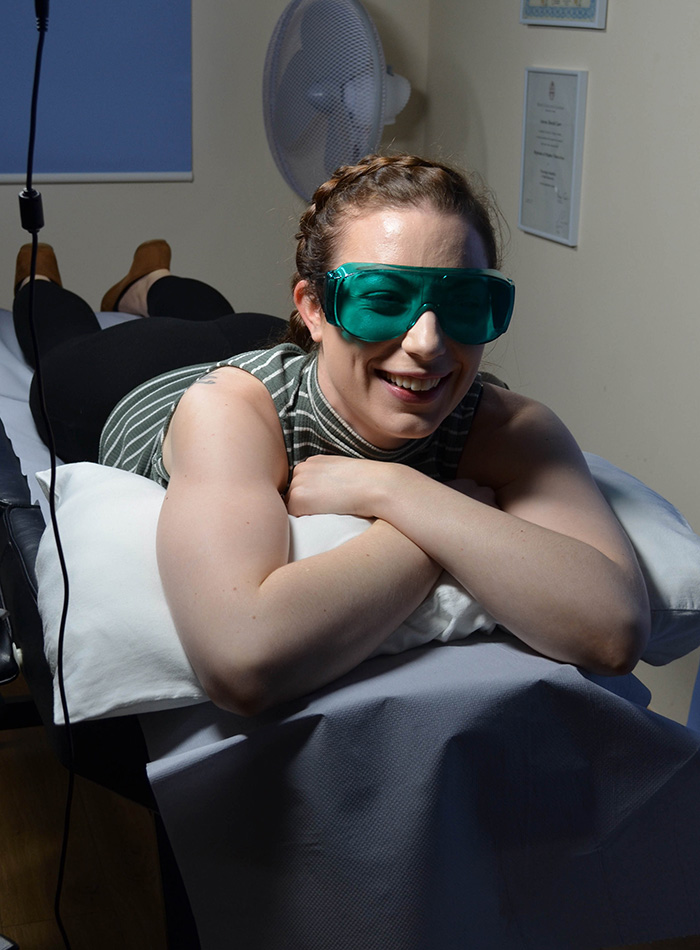 Scottish beauty in green goggles smiling while lying on treatment couch